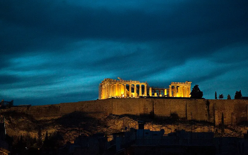 The illuminated Parthenon and Acropolis hill beneath a dark blue evening sky