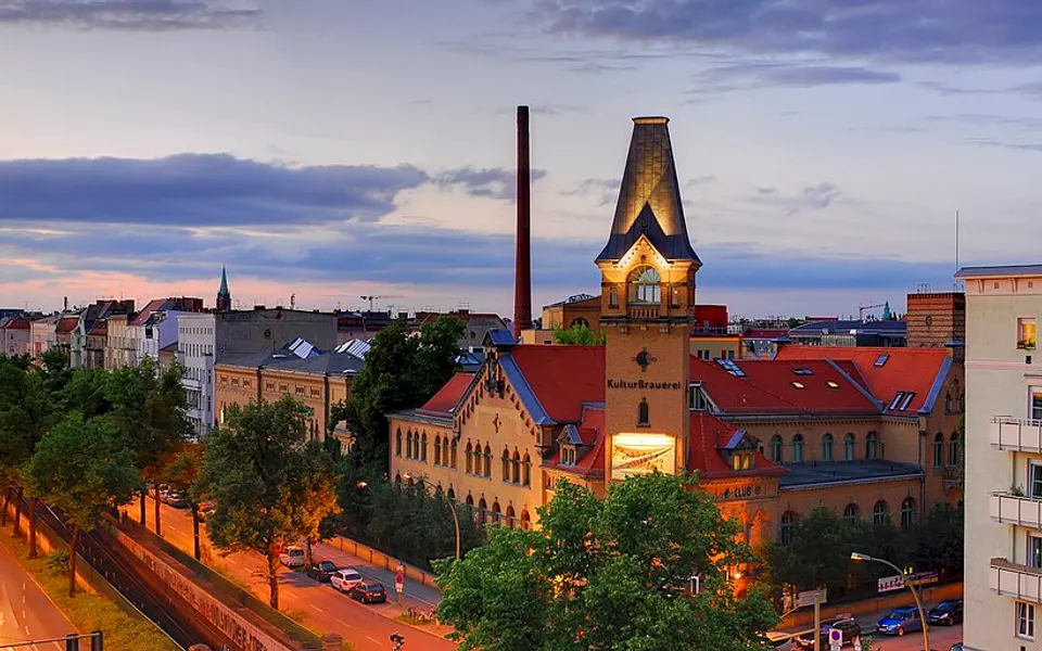 The illuminated Kulturbrauerei tower and surrounding Berlin streets at dusk