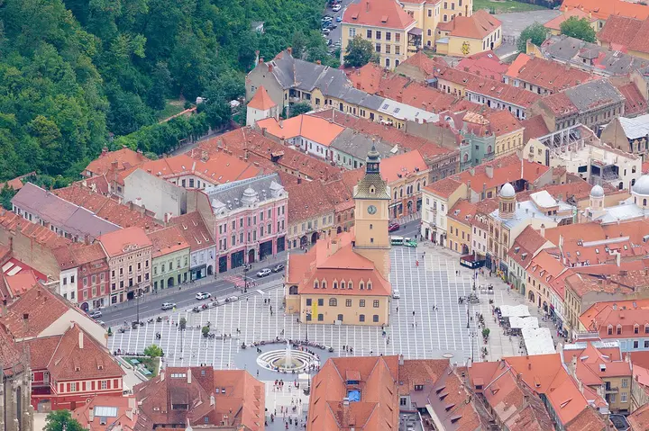 Red rooftops surrounding Council Square in Brașov, viewed from above.