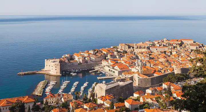 Orange rooftops and stone walls of Dubrovnik beside the sea.