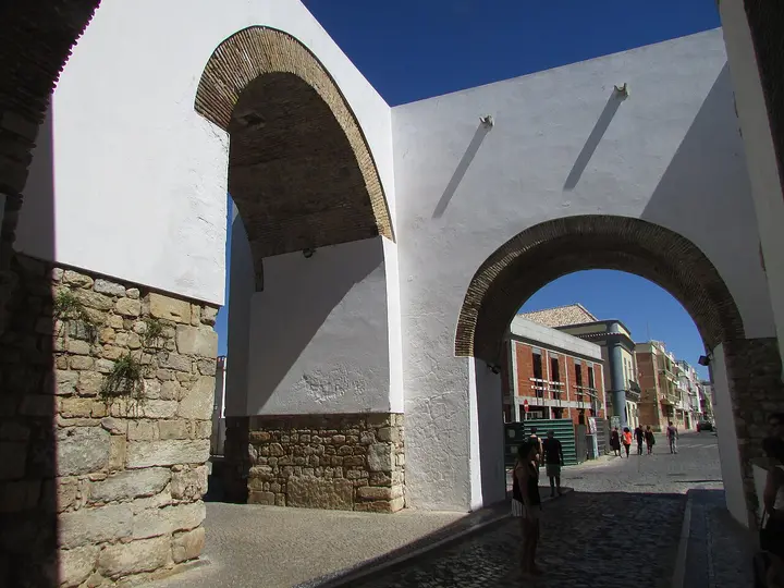Whitewashed stone gateway opening onto a street in Faro.