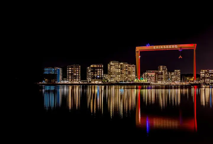 Illuminated Eriksberg crane and waterfront reflected in the water in Gothenburg.