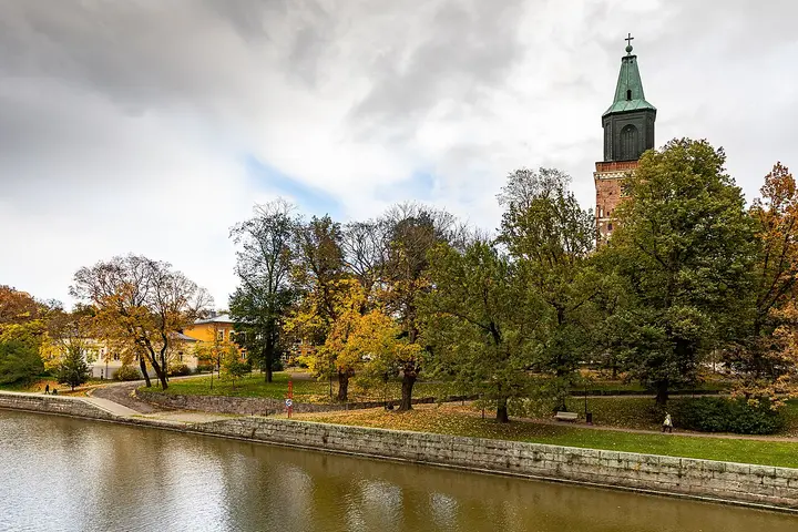 Turku Cathedral tower above autumn trees beside the river.