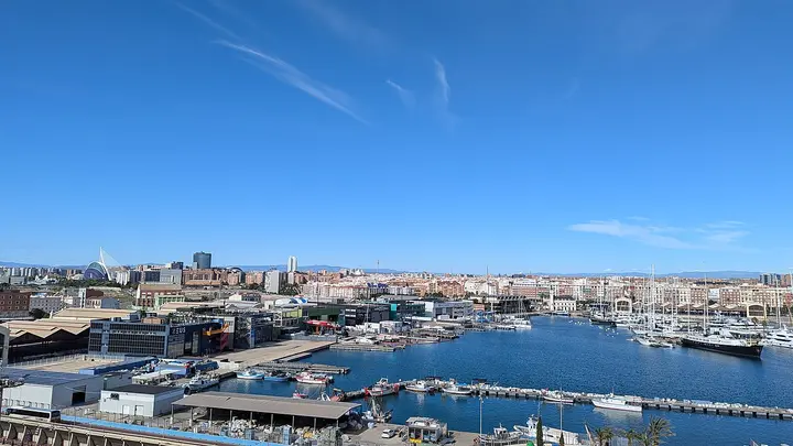 Boats and harbour buildings with the Valencia skyline beyond.