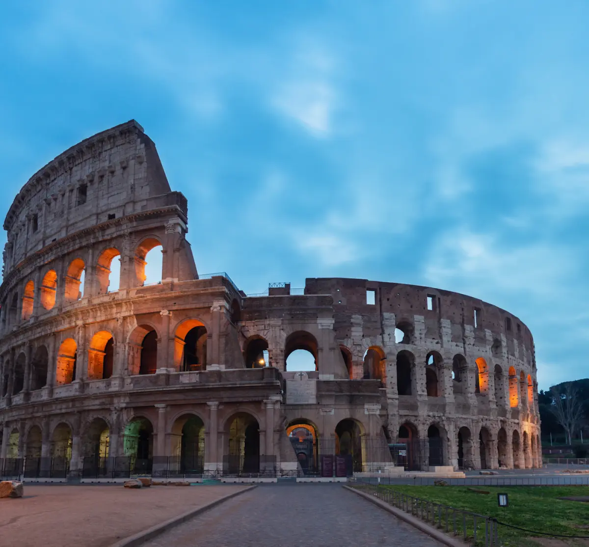 An evening by Rome’s Colosseum, its arches lit against the blue sky